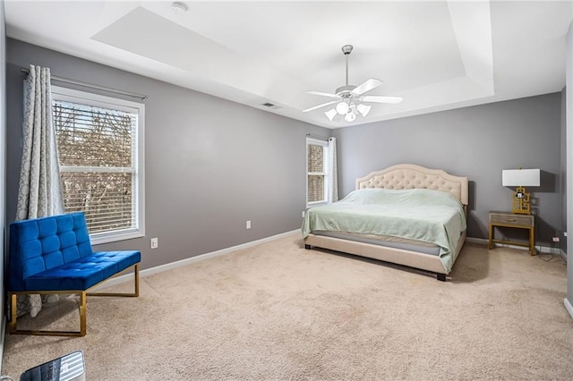 carpeted bedroom with ceiling fan, a raised ceiling, visible vents, and baseboards