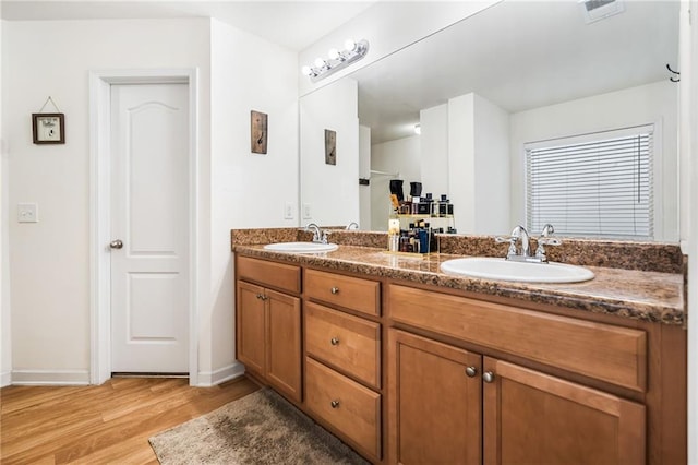 full bathroom featuring double vanity, visible vents, a sink, and wood finished floors