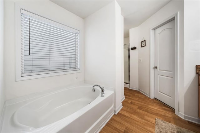 full bath with a garden tub, baseboards, wood finished floors, and a shower with shower door