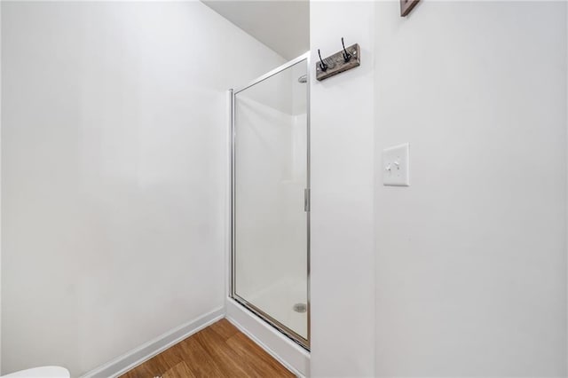 full bath featuring wood finished floors, a shower stall, and baseboards