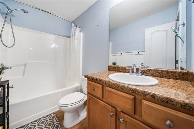 bathroom with toilet, a wainscoted wall, shower / tub combo, wood finished floors, and vanity