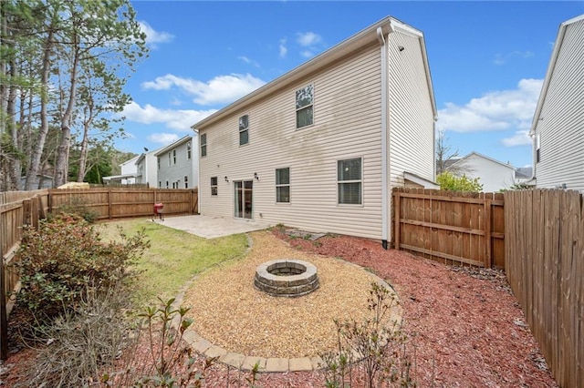 rear view of property with a fenced backyard, a fire pit, and a patio