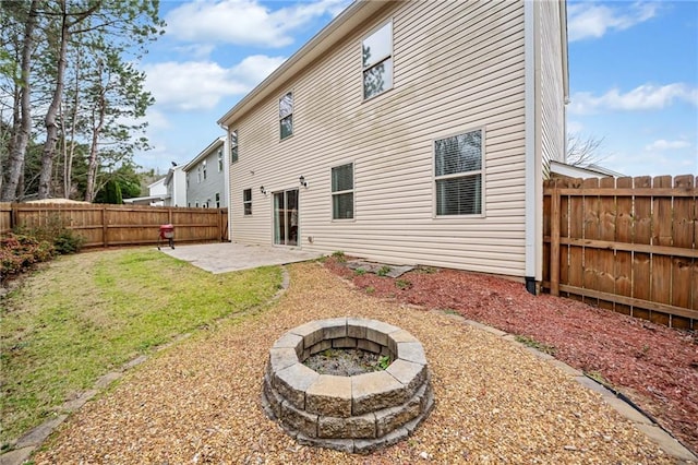 rear view of property with a fenced backyard, a fire pit, a lawn, and a patio