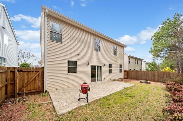 rear view of house featuring a patio, a lawn, a fenced backyard, and a gate