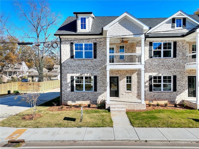 view of front of property with ceiling fan, a balcony, and a front yard