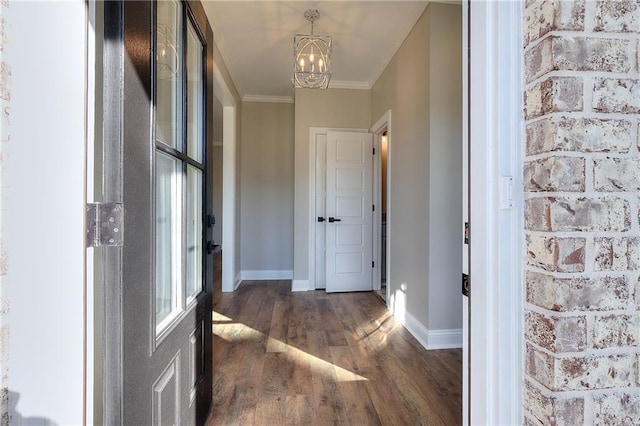 hallway with dark hardwood / wood-style floors, ornamental molding, and a chandelier