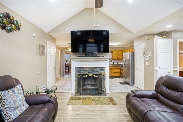 living room featuring a fireplace, light hardwood / wood-style floors, and vaulted ceiling