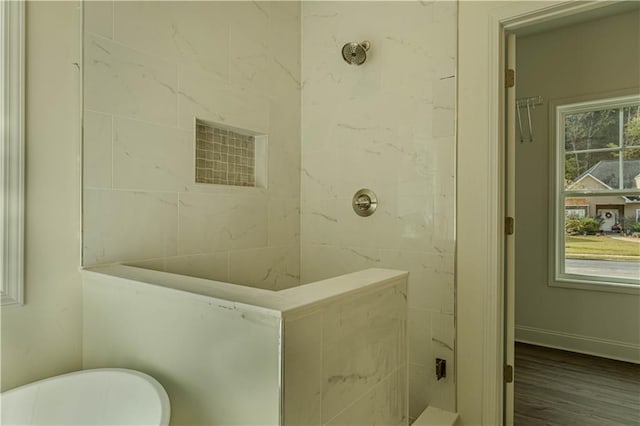 bathroom with tiled shower and hardwood / wood-style floors