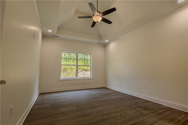 spare room with ornamental molding, dark wood-type flooring, a raised ceiling, and ceiling fan