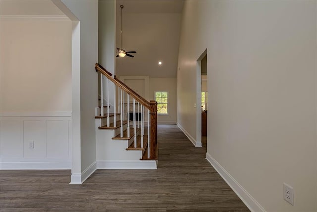 stairway featuring crown molding, hardwood / wood-style flooring, a towering ceiling, and ceiling fan