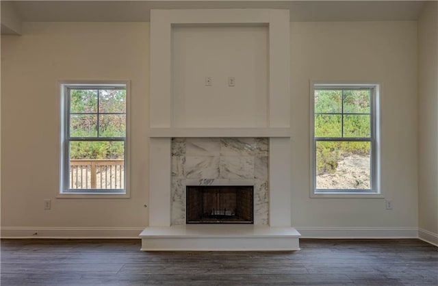 unfurnished living room with a wealth of natural light, dark hardwood / wood-style floors, and a high end fireplace