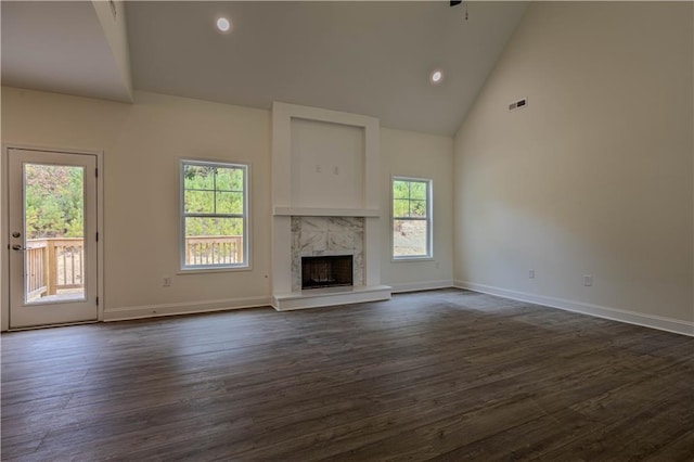 unfurnished living room featuring a high end fireplace, dark wood-type flooring, and plenty of natural light