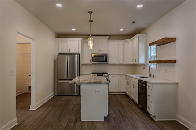 kitchen with appliances with stainless steel finishes, a kitchen island, white cabinetry, decorative light fixtures, and dark wood-type flooring