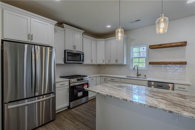 kitchen with hanging light fixtures, light stone counters, white cabinetry, sink, and stainless steel appliances