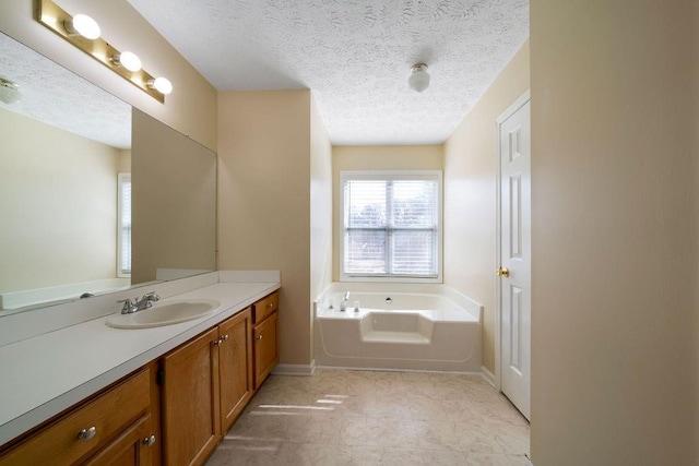 bathroom with a washtub, a textured ceiling, tile patterned flooring, and vanity