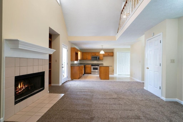 unfurnished living room featuring a high ceiling, a tile fireplace, and light colored carpet