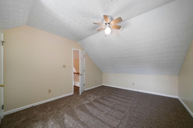 additional living space featuring a textured ceiling, ceiling fan, vaulted ceiling, and dark carpet