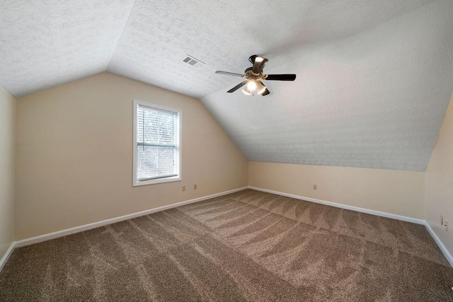 additional living space with lofted ceiling, carpet flooring, a textured ceiling, and ceiling fan