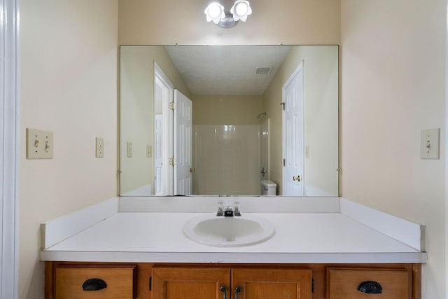 bathroom featuring toilet, walk in shower, and vanity