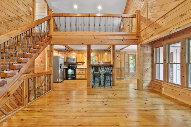 kitchen with stainless steel appliances, a towering ceiling, and light hardwood / wood-style flooring