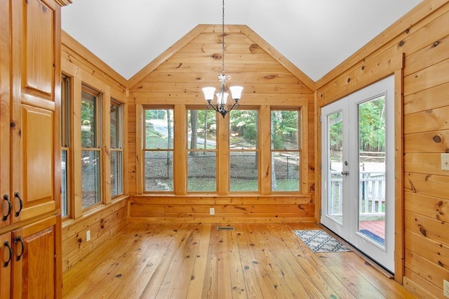 interior space featuring light hardwood / wood-style floors, an inviting chandelier, lofted ceiling, and wood walls