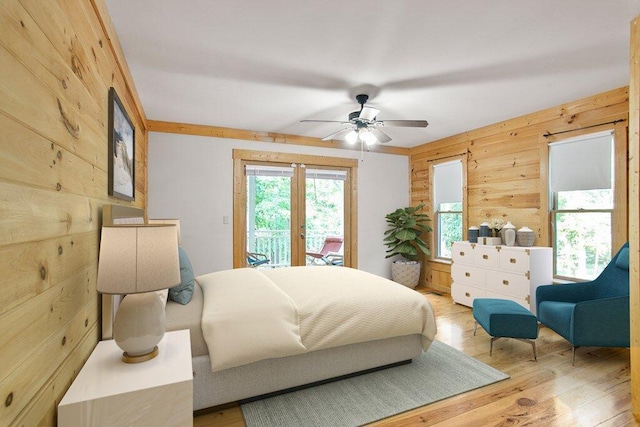 bedroom featuring wood walls, multiple windows, and light hardwood / wood-style floors