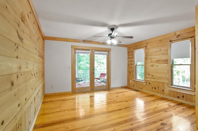 spare room with wood walls, light hardwood / wood-style flooring, and a wealth of natural light