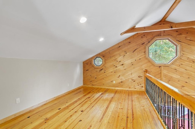 bonus room featuring light hardwood / wood-style floors, lofted ceiling with beams, and wooden walls