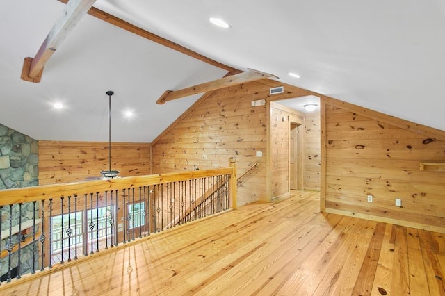 bonus room featuring wood walls, light wood-type flooring, ceiling fan, and vaulted ceiling