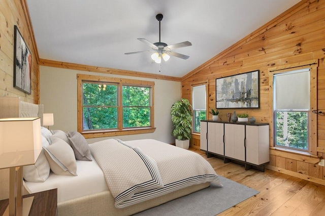 bedroom with light hardwood / wood-style floors, multiple windows, ceiling fan, and wooden walls