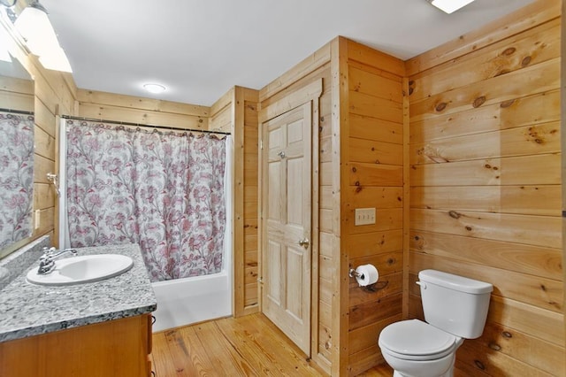 full bathroom featuring shower / bathtub combination with curtain, wooden walls, toilet, vanity, and wood-type flooring