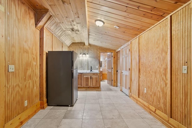 kitchen with light tile patterned flooring, vaulted ceiling with beams, wood walls, refrigerator, and wood ceiling