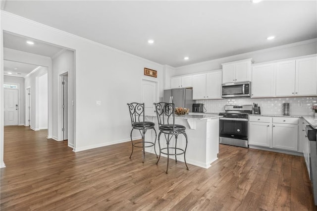 3135 Ellenton Dr, Lithia Springs, GA 30122 - kitchen with a breakfast bar area, backsplash, appliances with stainless steel finishes, and wood finished floors