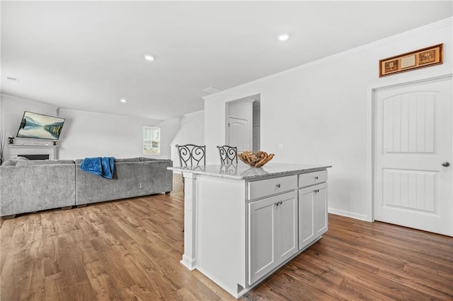 3135 Ellenton Dr, Lithia Springs, GA 30122 - kitchen with open floor plan, wood finished floors, a kitchen island, and ornamental molding