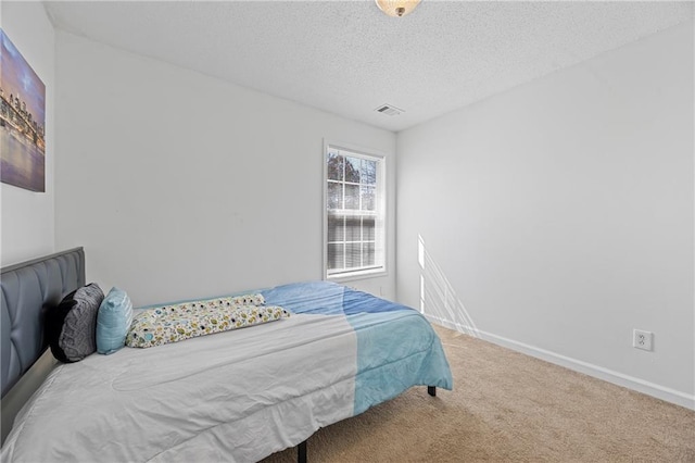 carpeted bedroom with a textured ceiling, visible vents, and baseboards