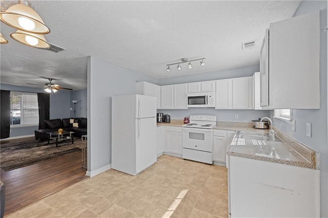 kitchen featuring white appliances, visible vents, light stone counters, white cabinetry, and a sink