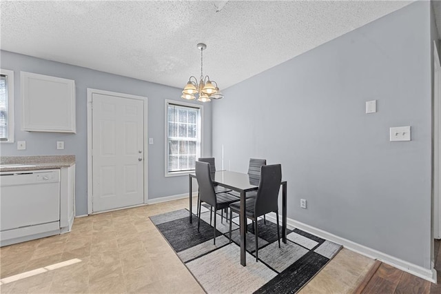 dining space with a chandelier, a textured ceiling, and baseboards