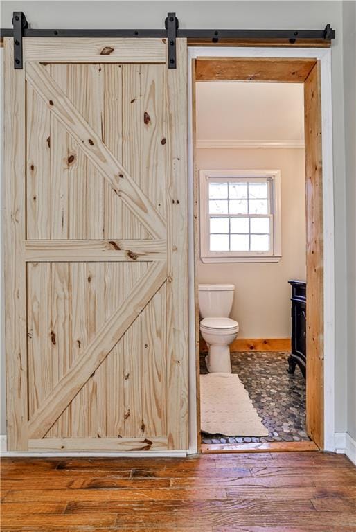 bathroom featuring hardwood / wood-style floors, ornamental molding, and toilet