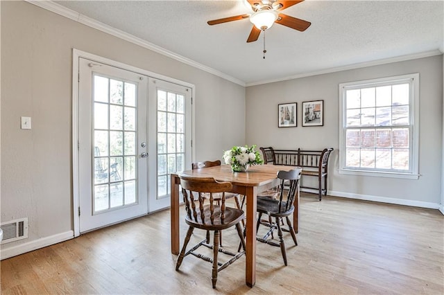 dining space featuring french doors, light hardwood / wood-style flooring, a textured ceiling, ornamental molding, and ceiling fan