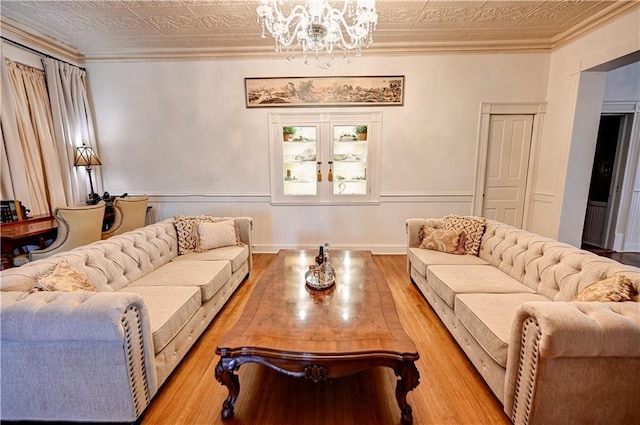 living room with light hardwood / wood-style floors, ornamental molding, and a chandelier