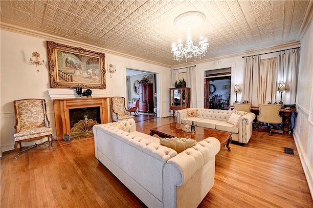 living room with an inviting chandelier, ornamental molding, and hardwood / wood-style floors