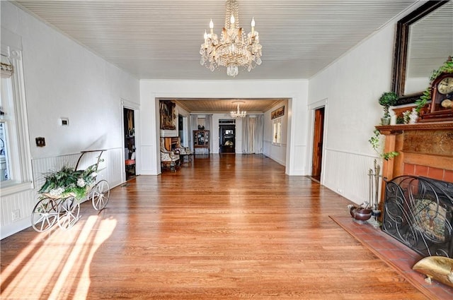 living room with light wood-type flooring, a tile fireplace, and an inviting chandelier