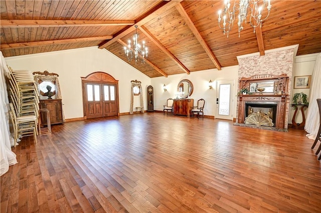 unfurnished living room with hardwood / wood-style floors, wooden ceiling, a notable chandelier, a large fireplace, and beamed ceiling