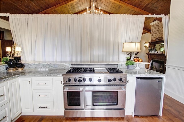 kitchen featuring hardwood / wood-style floors, white cabinetry, light stone countertops, stainless steel appliances, and a chandelier