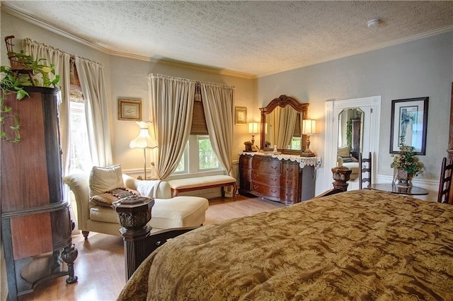 bedroom with ornamental molding, a textured ceiling, and light hardwood / wood-style floors