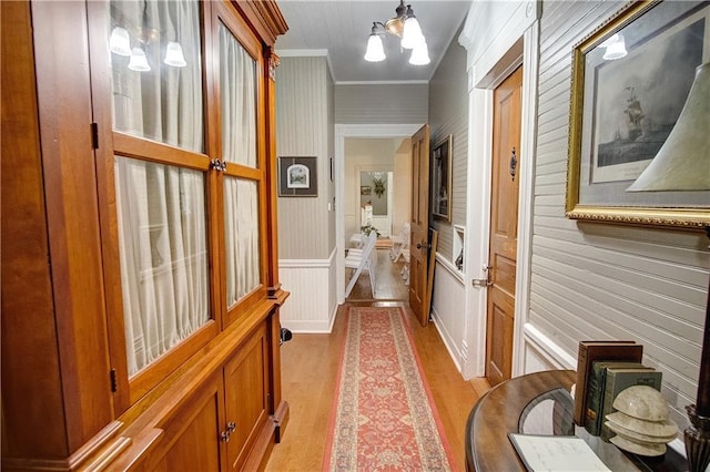 corridor featuring a notable chandelier, crown molding, and light hardwood / wood-style flooring