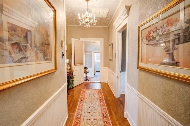 hall with an inviting chandelier, crown molding, and wood-type flooring