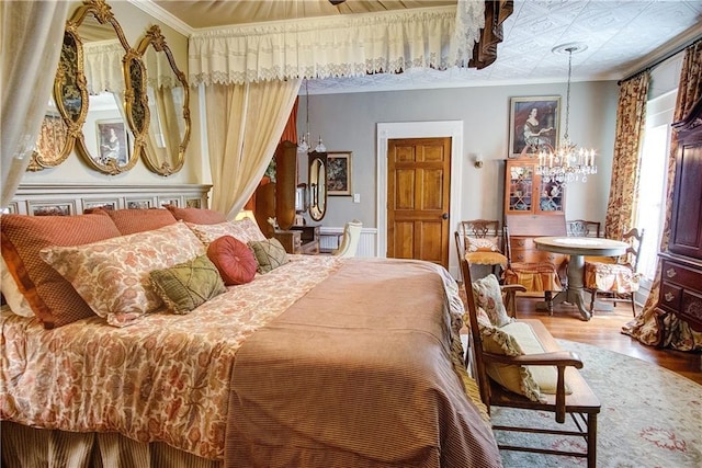 bedroom featuring an inviting chandelier, crown molding, and wood-type flooring