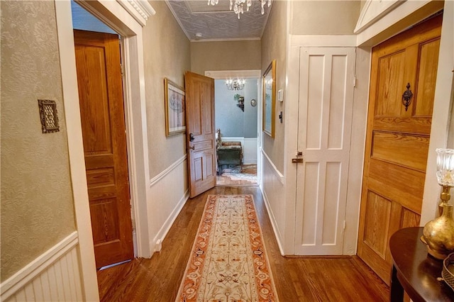 hall with wood-type flooring, a notable chandelier, and crown molding