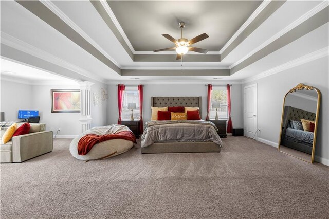 carpeted bedroom featuring ornamental molding, a tray ceiling, multiple windows, and baseboards